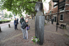 850748 Afbeelding van Jans Geesink-van Hussen (weduwe van Anton Geesink), die een krans legt bij het borstbeeld van ...